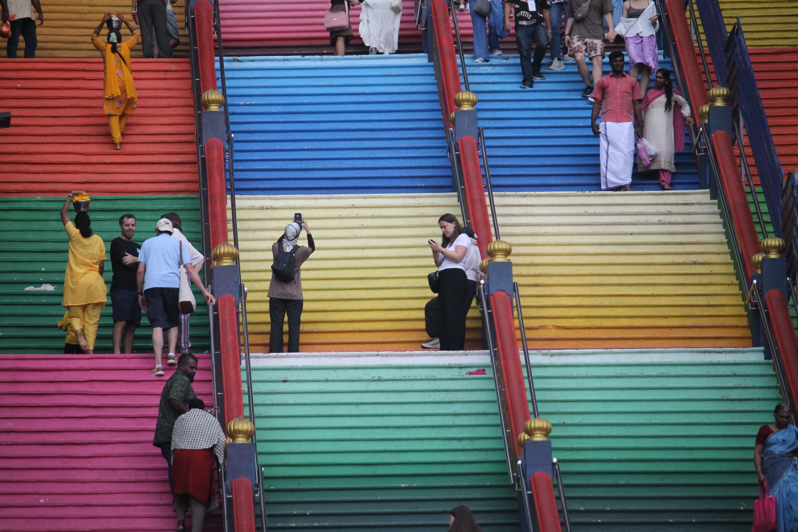 Besucherinnen und Besucher gehen auf der bunt bemalten Treppe der Batu Caves in Kuala Lumpur.