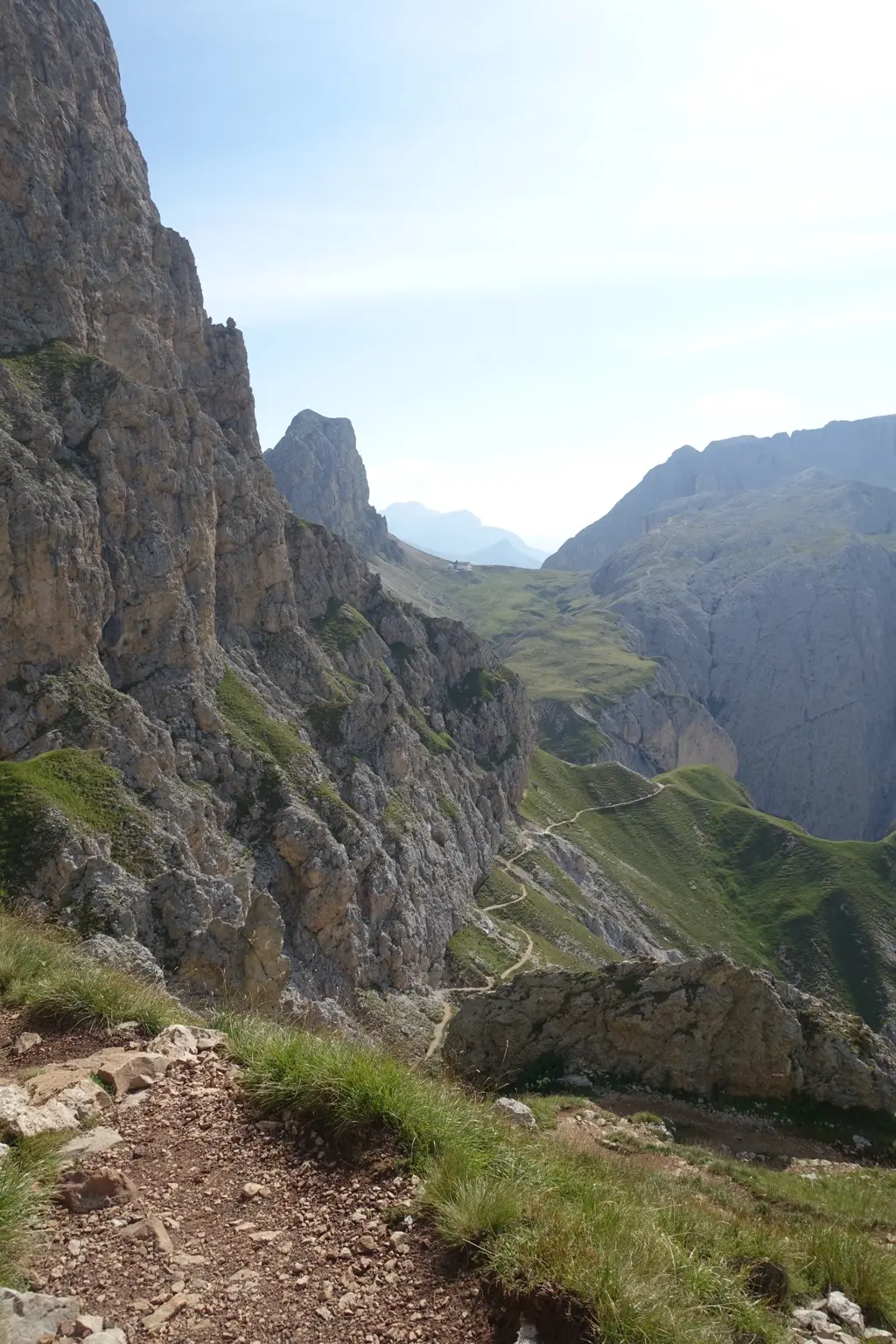 Schmaler Wanderweg zieht sich zwischen steilen Felswänden und grünen Berghängen durch die Dolomiten.