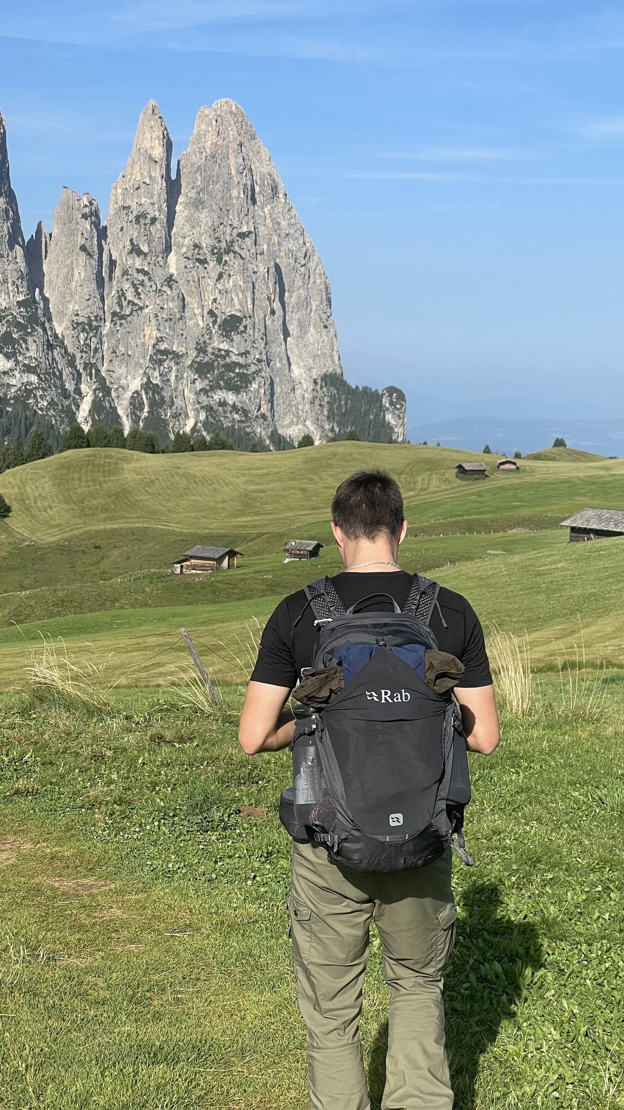 Wanderer mit großem Rucksack vor den Felstürmen des Schlern auf der Seiser Alm
