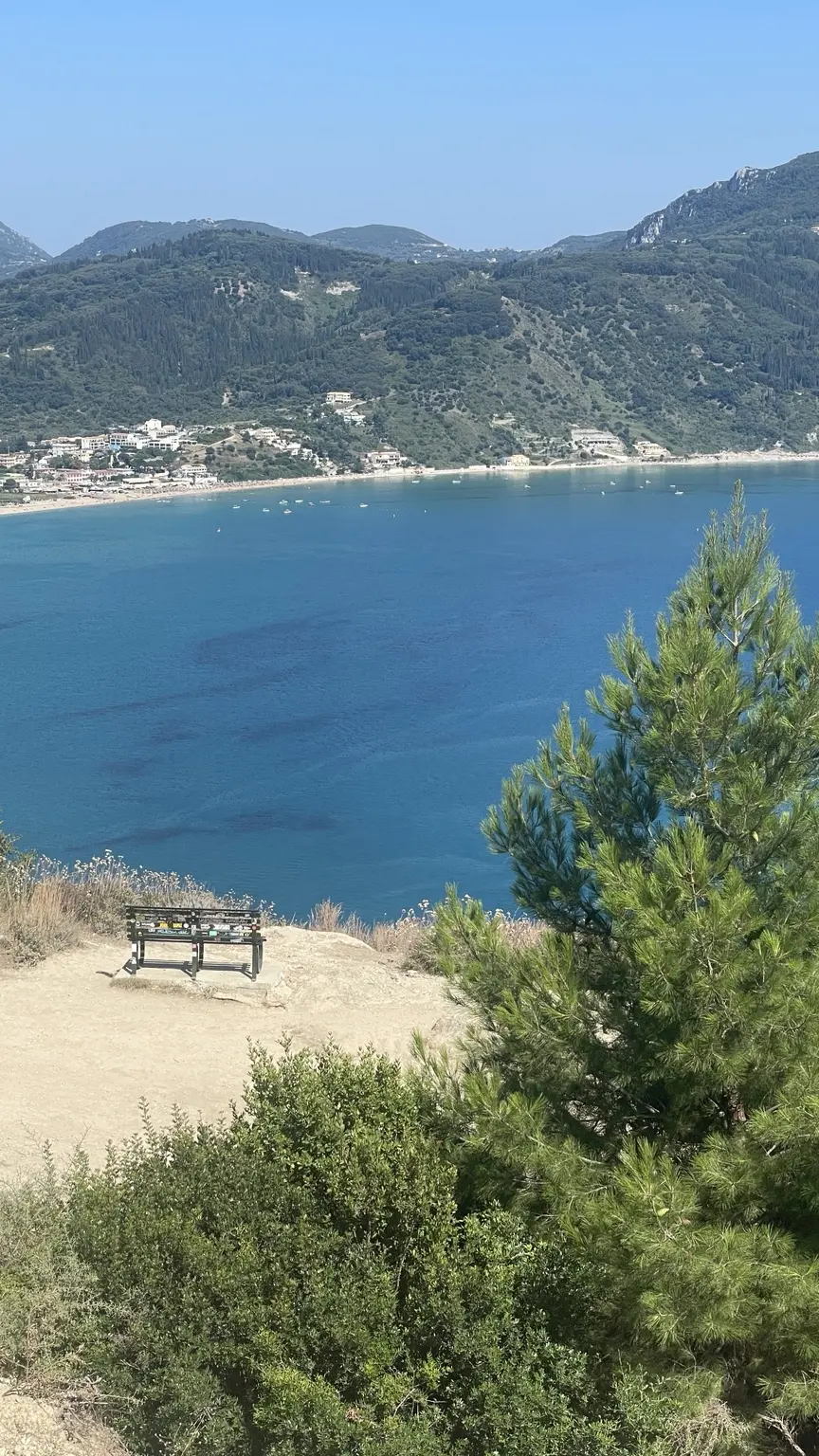 Blick über eine tiefblaue Bucht und grüne Berge auf Korfu