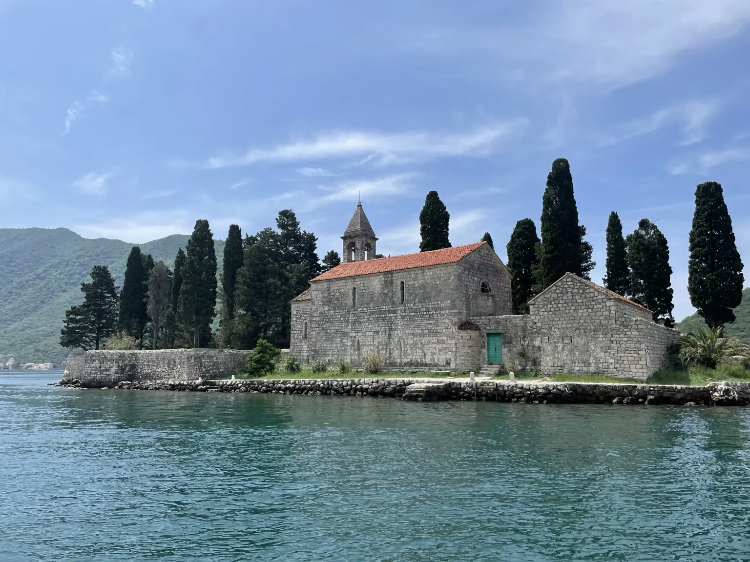 Steinerne Kirche auf einer kleinen, von Zypressen bewachsenen Insel vor Perast