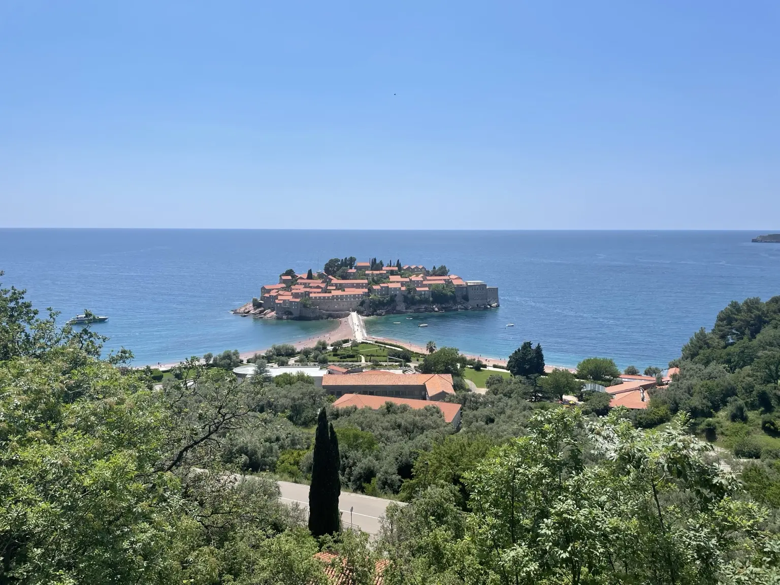 Blick über Bäume auf die Insel Sveti Stefan und die blaue Adria