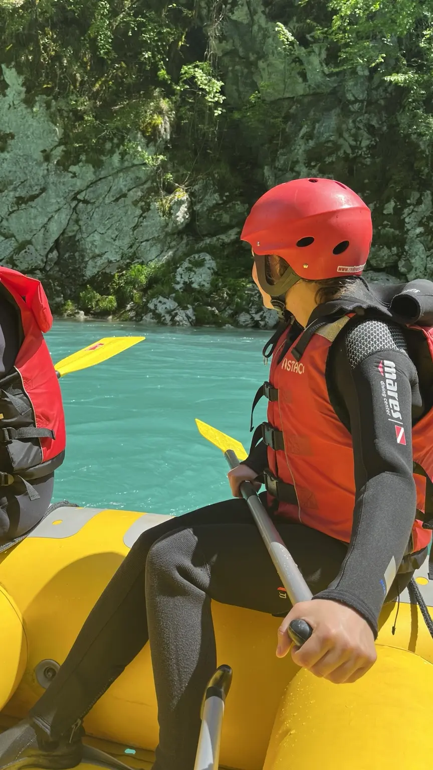 Rafterin mit rotem Helm und Schwimmweste in einem gelben Boot auf der türkisfarbenen Tara