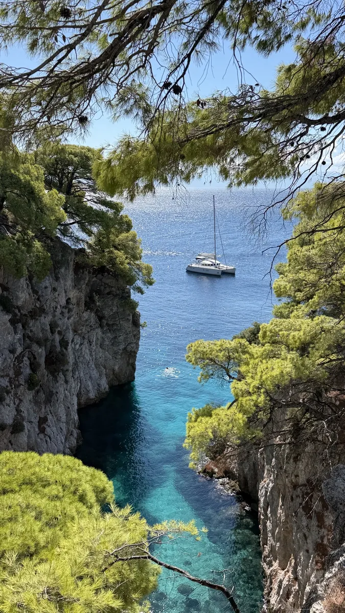 Türkisfarbene Felsbucht bei Amarandos mit einem Segelboot vor der Küste