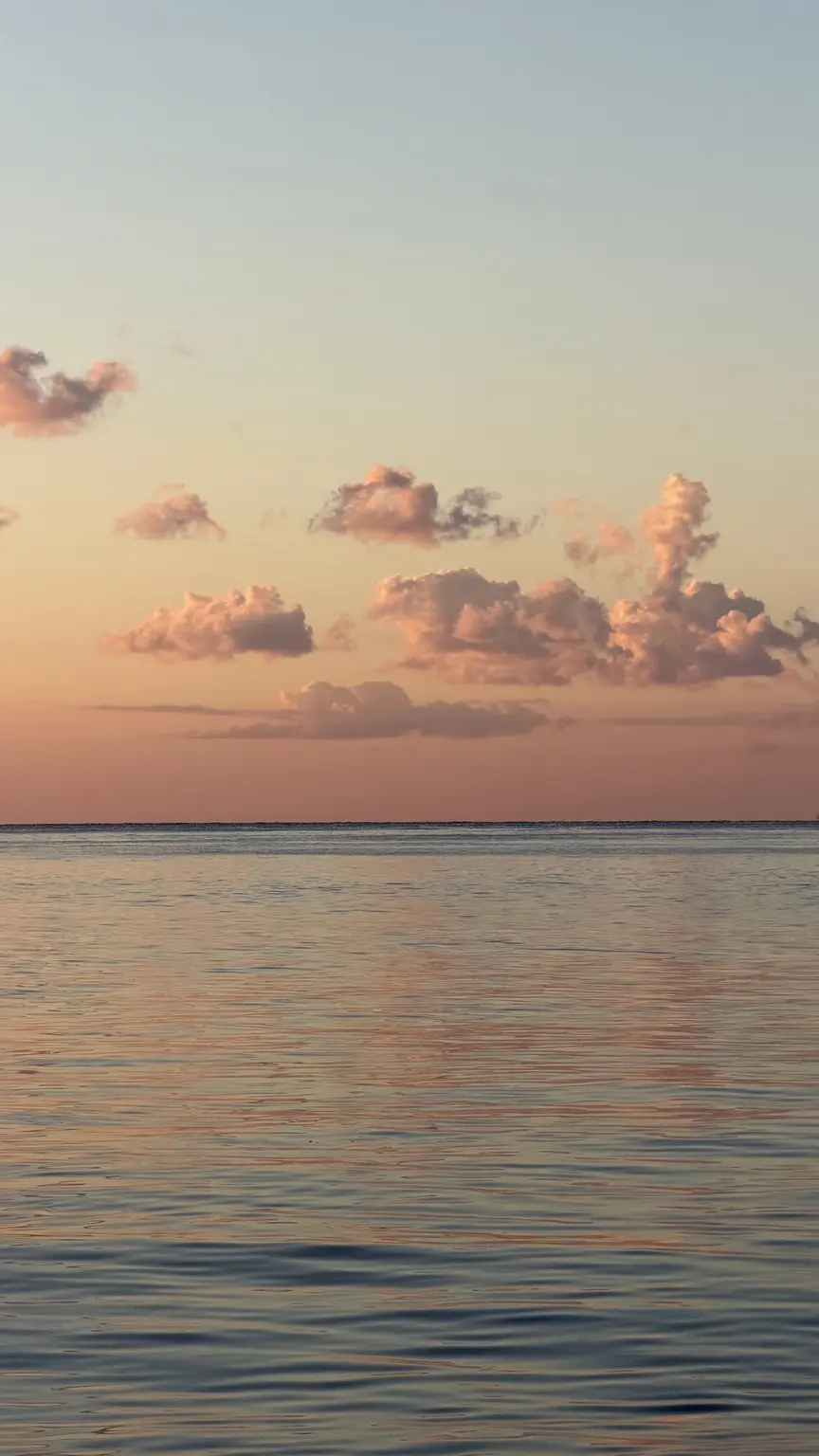 Apricotfarbenes Abendlicht über dem Meer, dessen Oberfläche die Farben des Himmels spiegelt