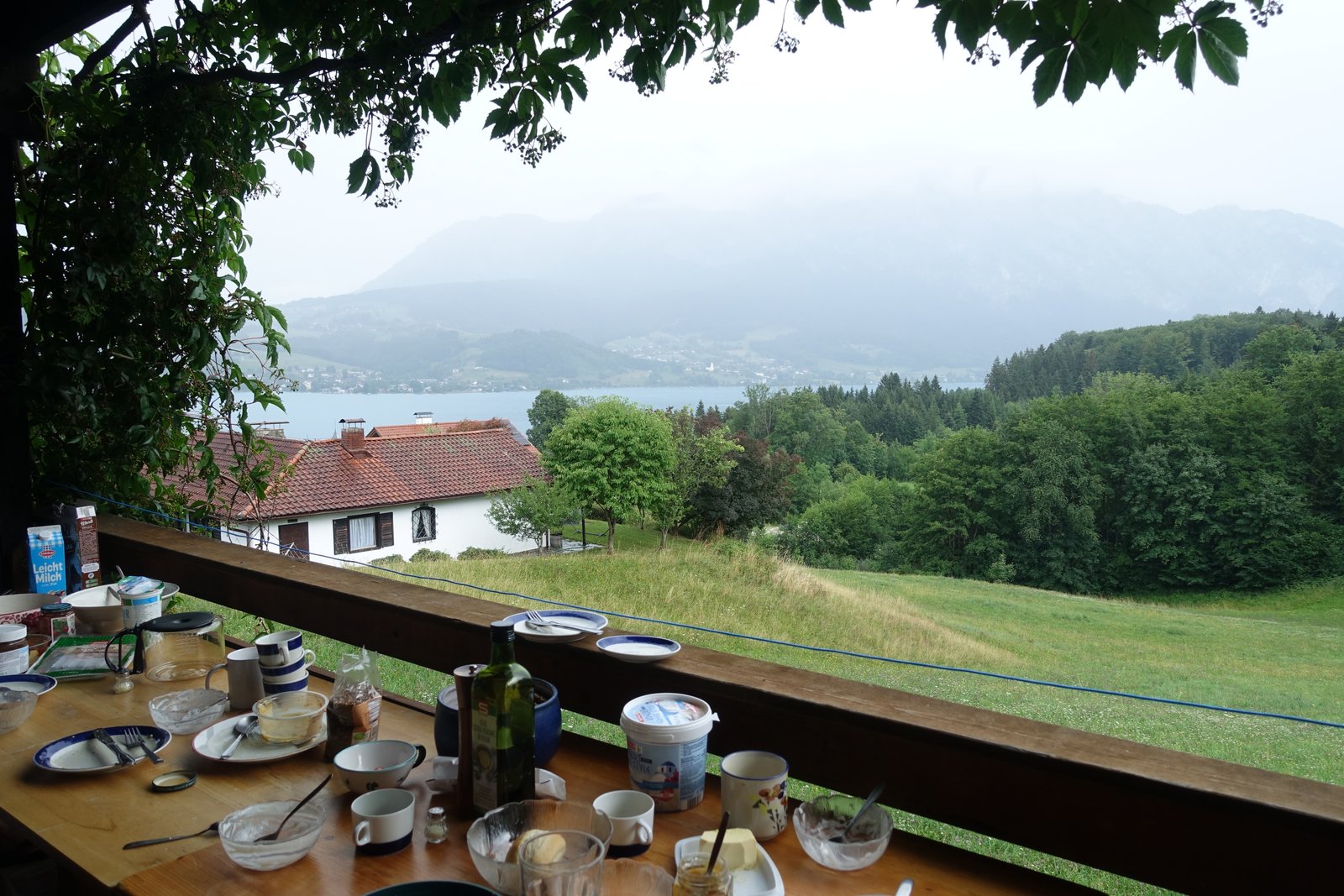 Frühstückstisch auf einer Terrasse mit Blick auf den Attersee und bewaldete Berge