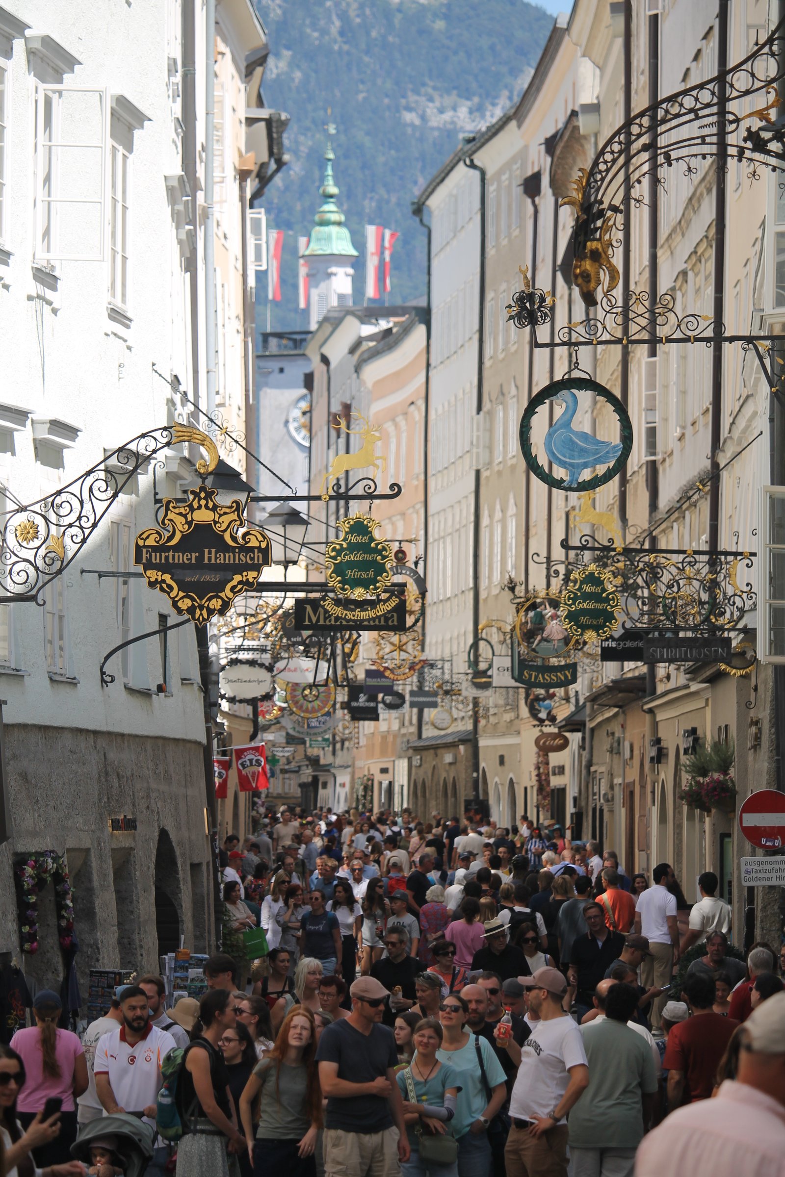 Belebte Getreidegasse in Salzburg mit historischen Zunftschildern
