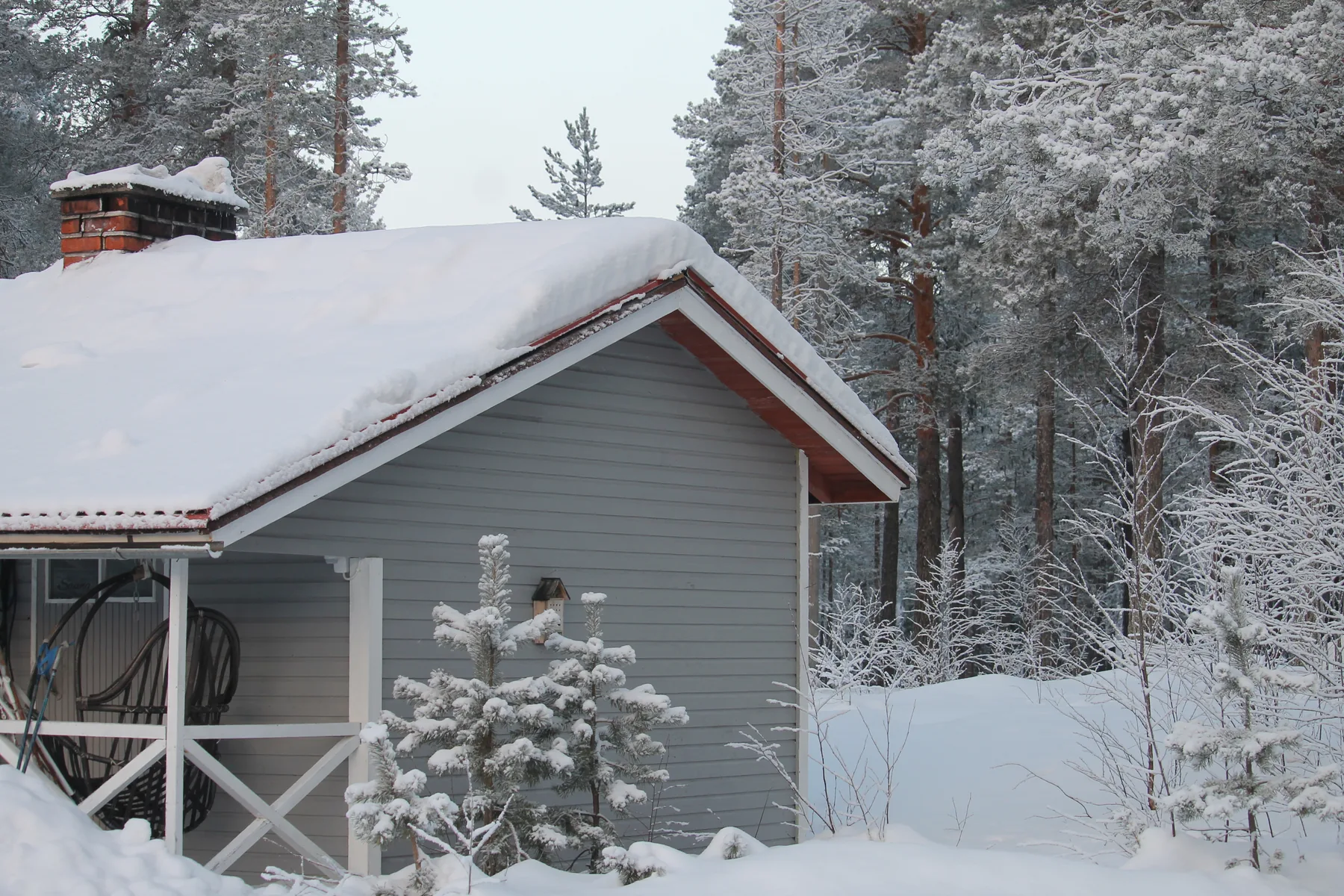 Verschneites Holzhaus am Waldrand im Raum Meltosjärvi